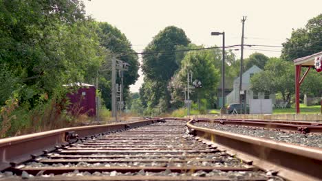 Looking-down-a-set-of-train-tracks-at-a-crossing-sign-wile-car-passes-by