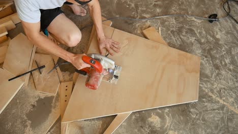 Worker-using-a-circular-saw-to-cut-a-piece-of-plywood-in-his-wood-working-workshop