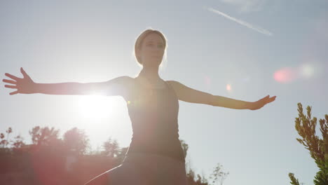 Mujer-Joven-Haciendo-Yoga-Afuera-Con-Luz-Solar-Fuerte-Detrás-De-Ella