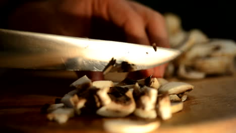 Cutting-champignons-on-a-wooden-breadboard-with-an-iron-knife