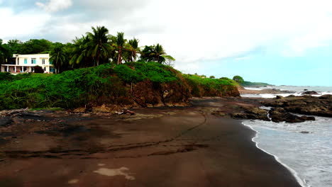 Drone-footage-of-Pacific-coastline-with-green-tropical-landscape-and-scatered-houses-in-Costa-Rica