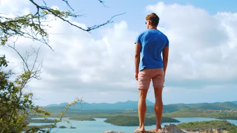 View-from-behind-of-young-man-standing-at-viewpoint-in-Curacao-overlooking-bay