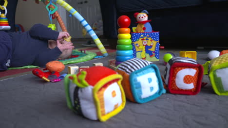 Baby-boy-rolling-around-on-the-floor,-playing-with-toys