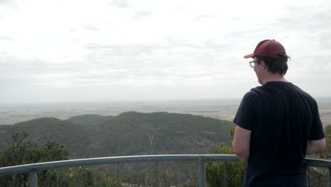 Man-looks-out-over-the-You-Yangs-National-Park,-Victoria-Australia