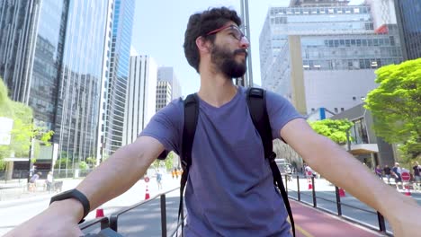 Handsome-young-bearded-man-on-bike-standing-on-the-bike-path-of-Paulista-Avenue-on-a-beautiful-sunny-day