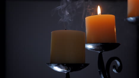 Man-blowing-out-a-single-candle-on-an-ornamental-candelabra
