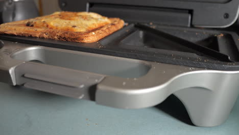 Cooked-ham-and-cheese-toasty-is-removed-from-the-sandwich-maker