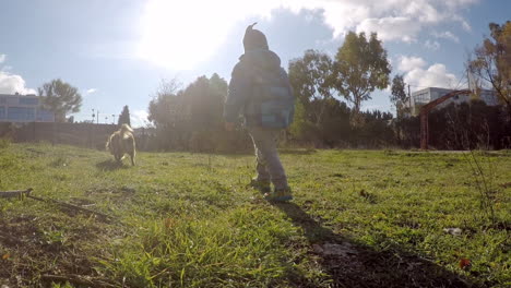 Kid-Running-in-a-Field-With-A-dog-Wide-Shot
