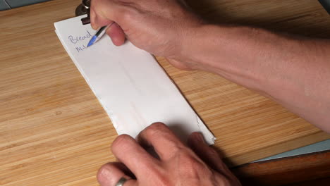 Man-writes-shopping-list-on-recycled-paper