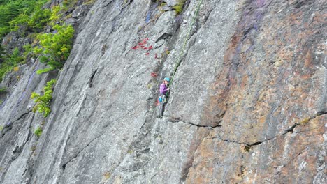 Aerial-footage-Close-up-of-young-female-climber-preparing-on-the-side-of-a-cliff-in-Maine