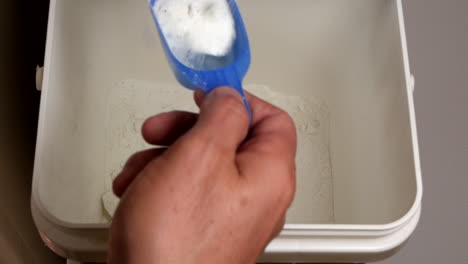Man-scoops-out-washing-detergent-with-a-measuring-cup-to-place-in-the-washing-machine