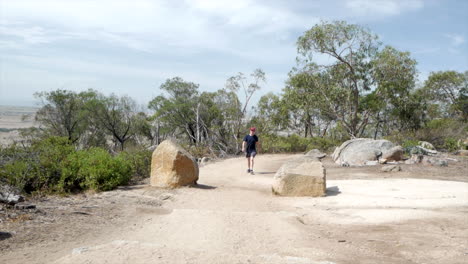 Man-walking-up-to-the-summit-of-the-You-Yangs-National-Park,-Victoria-Australia