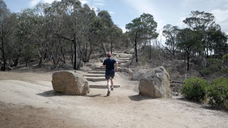 Hombre-Corriendo-Por-Los-Escalones-Hasta-La-Cumbre-Del-Parque-Nacional-You-Yangs,-Victoria-Australia