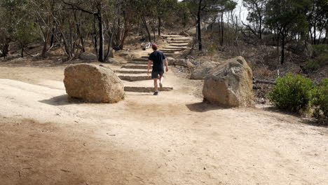 Hombre-Caminando-Hasta-La-Cima-Del-Parque-Nacional-You-Yangs,-Victoria-Australia