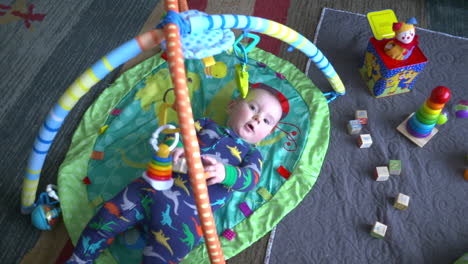 Top-down-shot-of-a-cute-baby-boy-actively-playing-with-toys-in-a-baby-gym