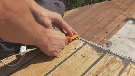Using-scraper-removing-residual-mastic-from-boat-roof-planks