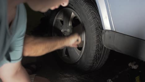 Replacing-car-tire-at-night-tightening-nuts-with-angled-wrench