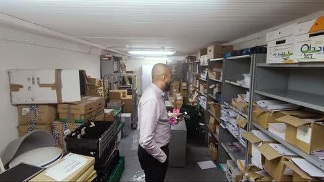 Asian-Indian-male-looking-for-something-in-office-storeroom-in-basement