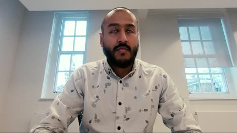 Asiatischer-Indischer-Mann,-Der-Sich-Im-Büro-Hinsetzt-Und-Auf-Den-Computerbildschirm-Schaut