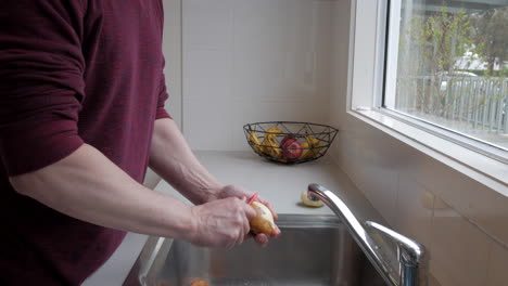 Mann-Schält-Kartoffeln-An-Einer-Küchenspüle