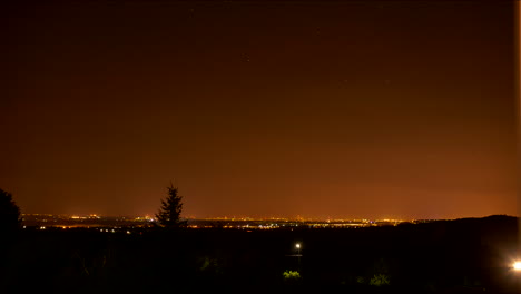 Time-lapse-starry-night-sky-and-distant-city-glowing-orange
