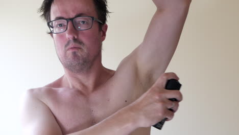 Caucasian-man-spraying-deodorant-onto-his-armpits-while-looking-into-a-mirror