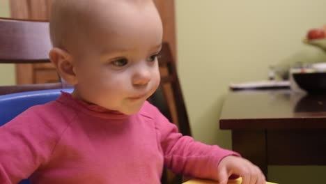 An-adorable-baby-girl-bounces-with-excitement-in-her-high-chair