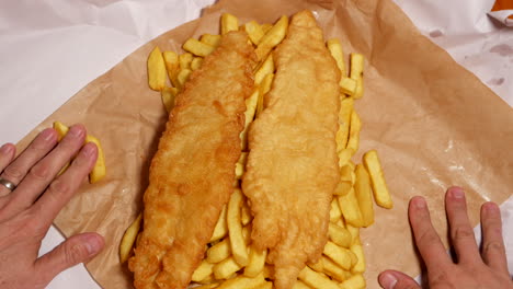 Man-opens-paper-wrapper-with-fish-and-chips-inside