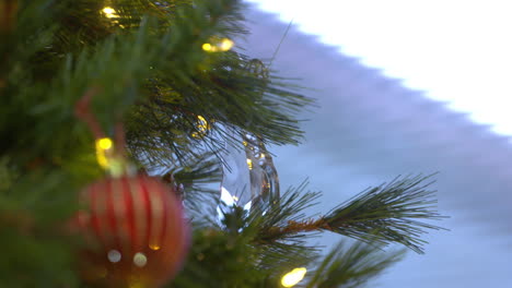 A-young-woman's-hand-hangs-a-glass-ornament-on-a-Christmas-tree