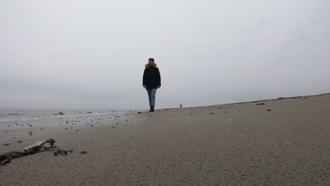 Man-walking-alone-on-the-beach-on-a-rainy-day