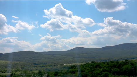 Nubes-De-Lapso-De-Tiempo-Moviéndose-Y-Cielo-Azul-Sobre-Colinas-Verdes