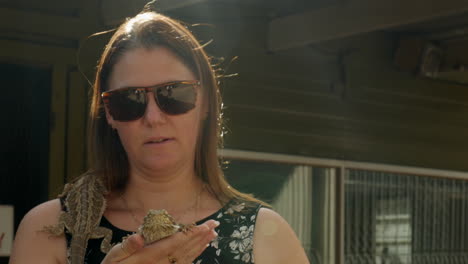 Woman-pats-a-Australian-bearded-dragon-lizard-while-another-reptile-sits-on-her-shoulder