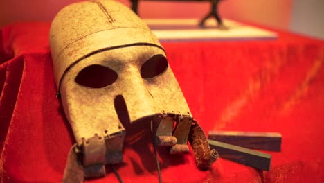 Artefacto-De-Máscara-Vikinga-En-Tela-Roja