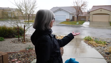 A-middle-aged-woman-checking-the-weather-and-feeling-the-winter-rain-drops-with-her-hand-in-slow-motion