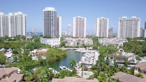 Backwards-Flyby-Aerial-Shot-of-Aventura-Florida-Marina,-Revealing-Beautiful-Luxury-Condos,-Yachts-and-Homes