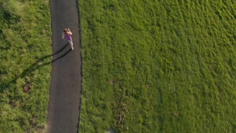 Aerial-of-Young-Woman-Running-on-a-Track-at-Sunset