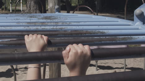 Slow-motion-close-up-of-a-child's-hands-as-she-hangs-from-monkey-bars-and-then-lets-go
