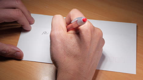Mann-Schreibt-Eine-Adresse-Auf-Einen-Weißen-Umschlag