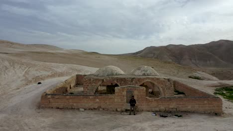 Sacar-Del-Hombre-De-Pie-Junto-A-Una-Antigua-Ruina-En-El-Desierto-De-Judea,-Israel