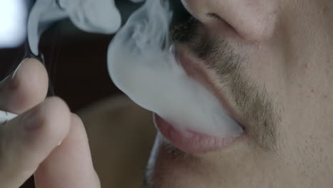 Close-up-of-young-man-smoking,-blowing-smoke