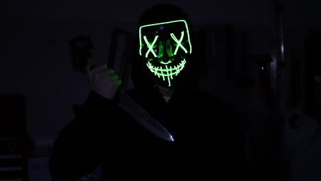 A-terrifying-slasher-killer-in-a-scary-horror-halloween-mask-pulling-a-knife-on-his-murder-victim-in-the-dark