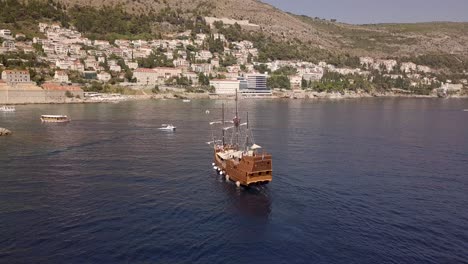 AERIAL:-Old-boat-cruising-in-Dubrovnik,-Croatia