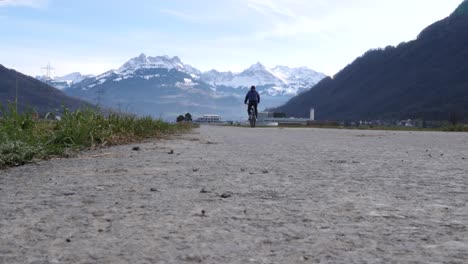 A-Cyclist-Riding-on-a-Road-in-the-Swiss-Alps-in-Bilten,-Switzerland,-Ground-Level