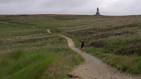 A-young-man-running-on-the-moors-at-Darwen-Tower,-Lancashire