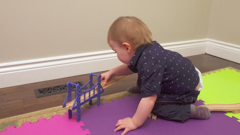 Baby-boy-putting-a-toy-train-track-together