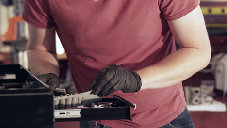 Tilt-Up-of-Young-Blonde-Man-Looking-Through-Tools-Drawer-in-Shop