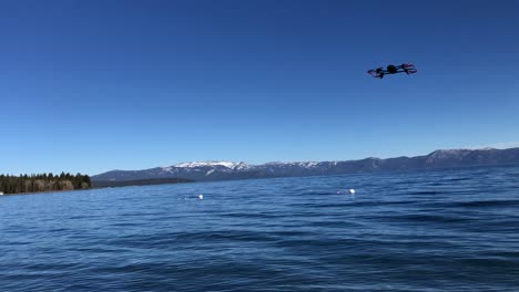 Drone-Moviéndose-Hacia-Arriba-Y-Hacia-Abajo-En-El-Aire-Con-Cielo-Azul-En-El-Fondo-Y-Lago-De-Agua-Debajo