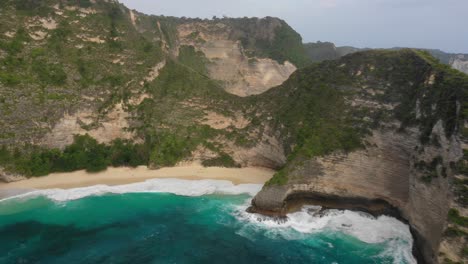 beautiful-secluded-sandy-Kelingking-beach-aerial-panorama,-drone-dolly-out-shot-revealing-cliffs-on-Nusa-Penida-Island,-Bali