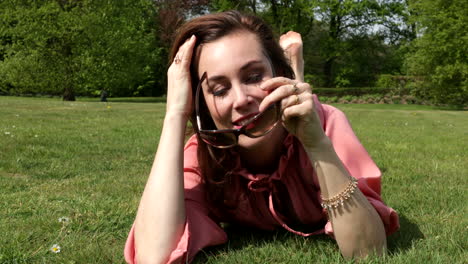 Attractive-adult-woman-rolling-playful-in-the-grass-en-putting-on-sunglasses