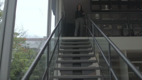 Middle-aged-adult-woman-walks-down-stairs-in-modern-style-home